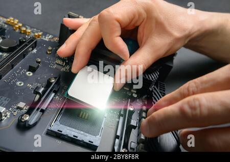 Hände eines Technikers Montage Computer-Hardware-Teile, wie eine neue glänzende cpu wird auf dem Motherboard montiert, Studio Nahaufnahme Stockfoto