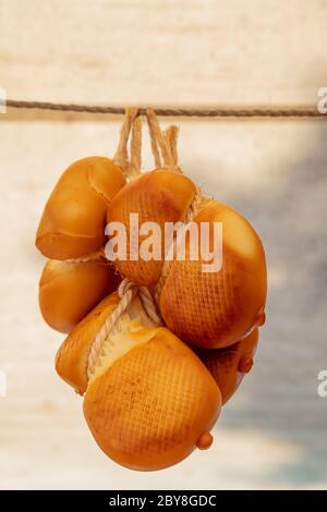 Close up Gruppe aus mehreren traditionellen geräucherten handwerklichen Italienische Scamorza affumicata Käse Köpfe hängen in Retail, Low Angle Seitenansicht Stockfoto