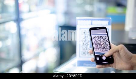 Männliche Hand Smartphone-Scan QR-Code Zahlung für digitales Zahlen ohne Geld Bargeld, und erhalten Sie den Kunststoff-Tag für Informationen, Online-Shopping, Bargeld Stockfoto