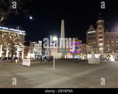 Dam Platz in Amsterdam bei Nacht mit beleuchteten menschenleeren Straßen und Gebäuden in den niederlanden Stockfoto