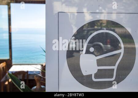 Quarantänezeichen "es ist obligatorisch, eine Maske innen tragen" an der Tür des Restaurants in Sizilien, Italien Stockfoto