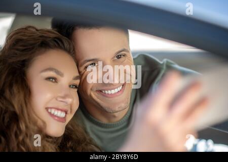 Junges Paar sitzt im Auto und macht Selfie Stockfoto