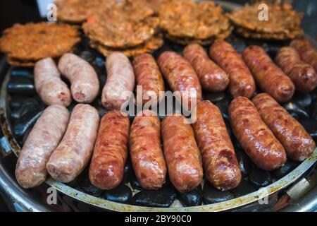 Braune und leckere Schwein- und Rinderwürste werden auf einem Grill auf einem Straßenmarkt in China gegrillt Stockfoto