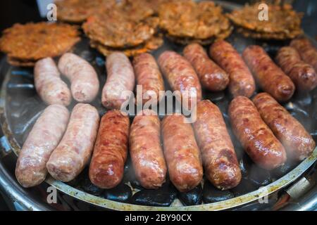 Braune und leckere Schwein- und Rinderwürste werden auf einem Grill auf einem Straßenmarkt in China gegrillt Stockfoto