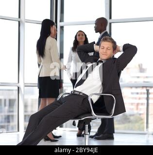 entspannende Manager im Büro mit Team im Hintergrund Stockfoto