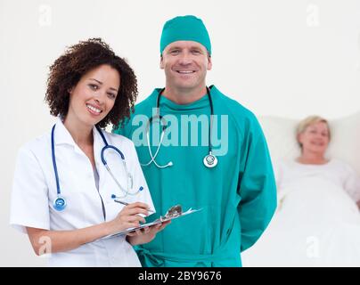 Charismatisches Team von Ärzten Patientin in ihrem Bett liegen Stockfoto