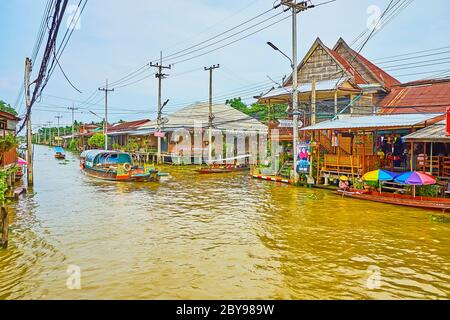 DAMNOEN SADUAK, THAILAND - 13. MAI 2019: Die Wasserstraße von Damnoen Saduak schwimmenden Markt mit Touristenboot und alten Holzhäusern auf Stelzen, am Mai Stockfoto