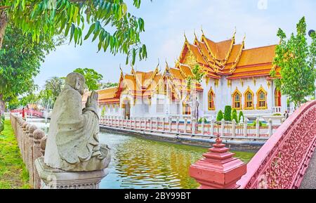 Der Blick auf Ubosot (Ordination Hall) des Wat Benchamabophit Dusitvanaram Marmor Tempel durch die kleine Steinskulptur am Ufer des schmalen khlong, Stockfoto