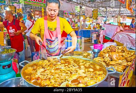 BANGKOK, THAILAND - 13. MAI 2019: Der Koch in der großen Pfanne mit kochendem Eintopf aus gerösteten Rind Innereien und Stierhoden, Talad Saphan Phut Markt, Dusit, Stockfoto