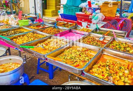 Die Theke des Straßencafés ist voll von Metallbecken mit gebratenem Fleisch, Hühnereintopf mit Gemüse, Seeschnecken in würziger Sauce und anderen thailändischen Gerichten, M Stockfoto