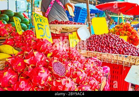 Die Haufen exotischer Drachenfrüchte (Pitaya), Kirschpflaumen und Rambutans auf dem Tresen des kleinen Bauernstandes des Mahanak Fruit Market, Bangkok, Thailand Stockfoto