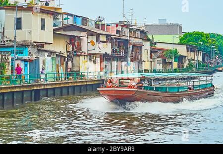 BANGKOK, THAILAND - 13. MAI 2019: Die alte Holzfähre schwebt durch den Khlong Maha Nak Kanal, gesäumt von alten Slums, verfallenen und schäbigen Hou Stockfoto