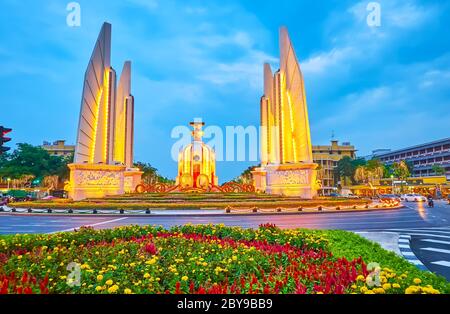 BANGKOK, THAILAND - 13. MAI 2019: Der Dämmerungshimmel über dem illuminierten Democracy Monument, umgeben von bunten Blumenbeeten, am 13. Mai in Bangkok Stockfoto