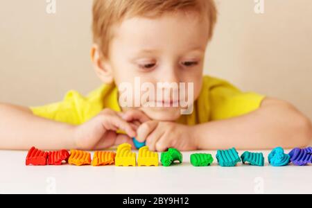 Kaukasische Baby blonde Skulpturen aus Kinderteig für die Bildhauerei zu Hause am Tisch, Kinder und Kreativität, die Entwicklung von Feinmotorik. Stockfoto