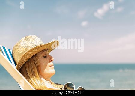 Frau auf einer Liege in der Sonne, französisch Küste Stockfoto