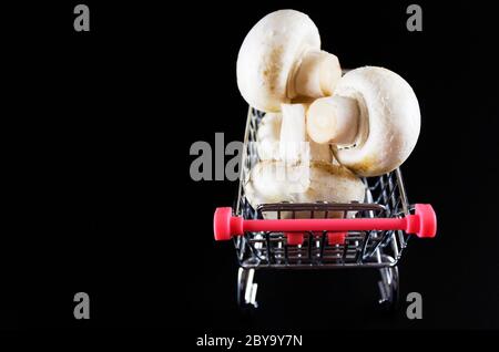 Champignon-Pilze in einem Wagen auf schwarzem Hintergrund Stockfoto