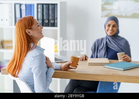 Frauen erzählen lustige Geschichten und trinken Kaffee während einer Pause Stockfoto