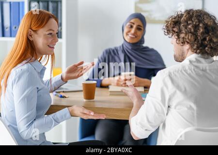 Arbeitskollegen hängen zusammen, trinken Kaffee und unterhalten sich Stockfoto