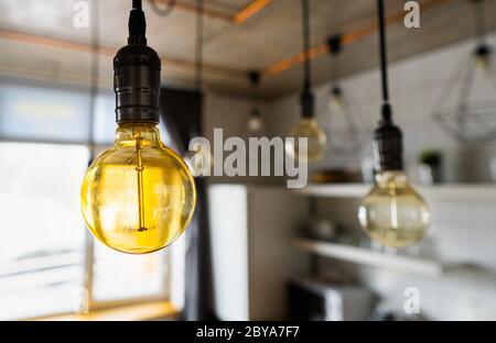 Große Vintage Glühbirnen hängen in der modernen Küche. Ineffiziente Glühlampen verschwenden Strom. Dekorative antike edison-Leuchte Stockfoto