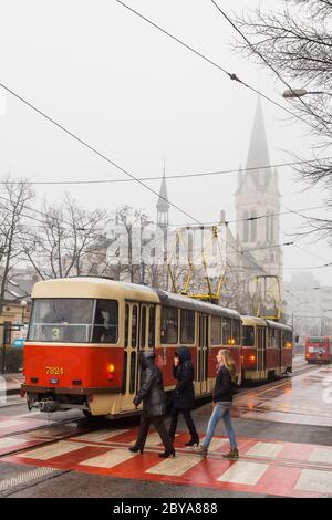 Frauen überqueren die Straße hinter einer Straßenbahn in Bratislava, Slowakei im Februar 2015. Stockfoto