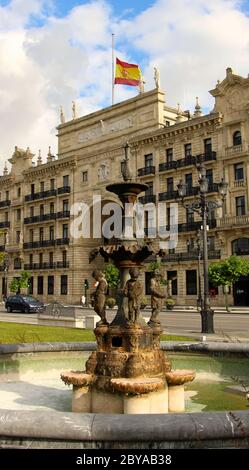 Ursprüngliches Hauptquartier der Bank Santander (Banco de Santander) spanische Nationalflagge am Halbmast und ein rostiger Brunnen aus den Gärten von Pereda Stockfoto