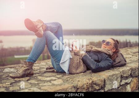 Junge Frau trinkend Kaffeetelefon auf der Festung Stockfoto