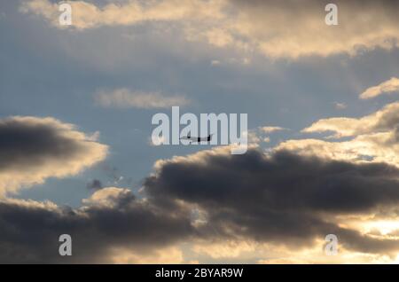 FLUG 419: Kommerzielle Flugzeuge starten von einem nahe gelegenen Newark International Airport in New Jersey in die untergehende Wolkenlandschaft an einem Frühlingstag. Stockfoto