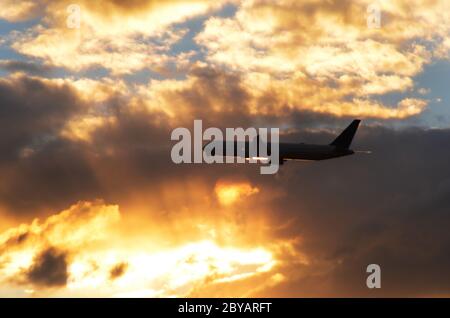 FLUG 419: Kommerzielle Flugzeuge starten von einem nahe gelegenen Newark International Airport in New Jersey in die untergehende Wolkenlandschaft an einem Frühlingstag. Stockfoto