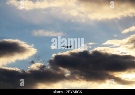 FLUG 419: Kommerzielle Flugzeuge starten von einem nahe gelegenen Newark International Airport in New Jersey in die untergehende Wolkenlandschaft an einem Frühlingstag. Stockfoto