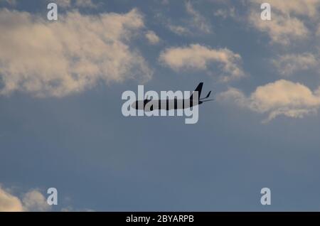 FLUG 419: Kommerzielle Flugzeuge starten von einem nahe gelegenen Newark International Airport in New Jersey in die untergehende Wolkenlandschaft an einem Frühlingstag. Stockfoto