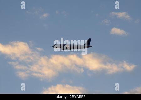 FLUG 419: Kommerzielle Flugzeuge starten von einem nahe gelegenen Newark International Airport in New Jersey in die untergehende Wolkenlandschaft an einem Frühlingstag. Stockfoto