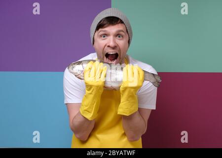 Glücklicher Fischer, der mit erfreulichem Ausdruck an seinem großen Fisch sucht, der Welle des Stolzes fühlt. Studioaufnahme Stockfoto