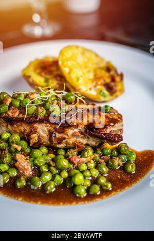 Gebratenes Kalbsfleisch mit Erbsenfleisch und Gratin-Kartoffeln auf Holztisch Stockfoto