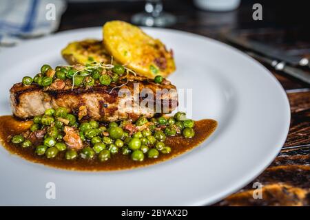 Gebratenes Kalbsfleisch mit Erbsenfleisch und Gratin-Kartoffeln auf Holztisch Stockfoto