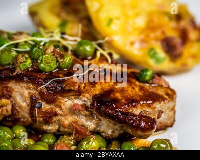 Gebratenes Kalbsfleisch mit Erbsenfleisch und Gratin-Kartoffeln auf Holztisch Stockfoto