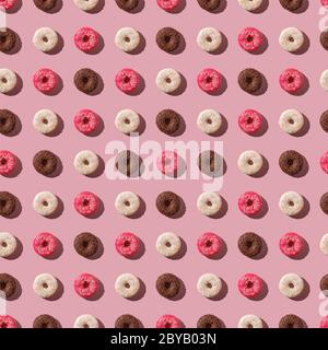 Rosa, Vanille und Schokolade Donuts mit Streuseln, nahtlose Muster, süß glasierte Dessert-Food auf rosa minimalem Hintergrund, Draufsicht Stockfoto