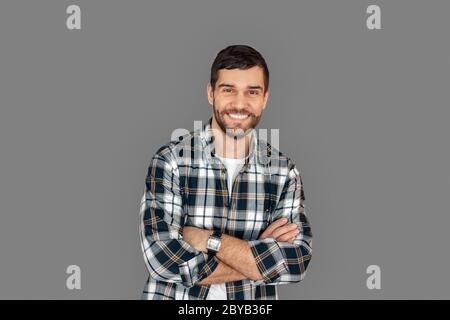 Freistil. Junger Mann im karierten Hemd stehend isoliert auf grauen verschränkten Armen lachend fröhlich Stockfoto