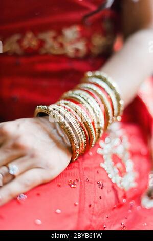 Indische Braut mit Arm voller roter und goldener Armreifen Stockfoto