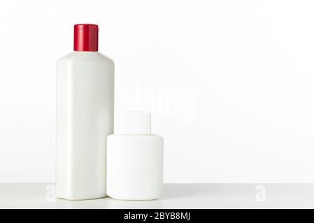 Zwei namenlose Plastikflaschen von weißer Farbe unter einem kosmetischen Produkt auf einem weißen Hintergrund mit Platz für Text Stockfoto