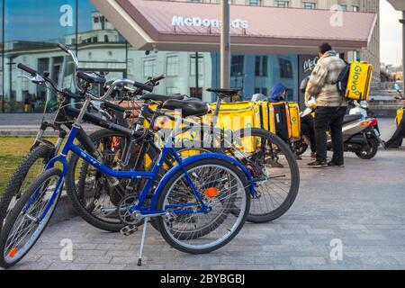 Kiew, Ukraine - 8. April 2020: Die gelben Glovo-Kuriere warten auf Bestellungen in der Nähe des Gebäudes der McDonald's-Restaurantkette. Kurierdienste sind besonders relevant in der Quarantäne. Stockfoto