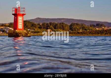 Leuchthaus in Ria de Pontevedra mit einer Straße und Bergen im Hintergrund Stockfoto