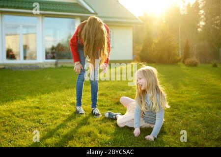 Zwei süße Schwestern um gemeinsam zum Narren auf dem Gras an einem sonnigen Sommertag. Kinder, albern und Spaß zu haben. Zeit mit der Familie. Stockfoto