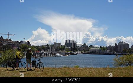 Ein Paar Radfahrer genießen den Blick über den Binnenhafen in der Innenstadt von Victoria, British Columbia, Kanada auf Vancouver Island und schauen auf die Do Stockfoto