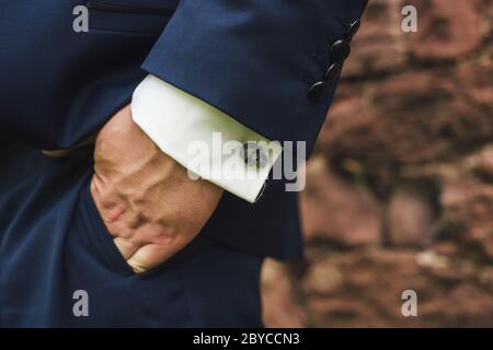 Nahaufnahme von Manschettenknöpfen in Form eines Schädels. Mann in blauem Anzug mit Hand in der Tasche. Mode-Accessoires für Herren. Kopierbereich Stockfoto