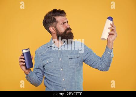 Die Behandlung mit individueller Betreuung. Hipster halten Haar Shampoo und Conditioner gelben Hintergrund. Haar Behandlung. Shampoonieren und Klimaanlage. Bart Behandlung Produkte. Haut Behandlung. Hautpflege. Stockfoto