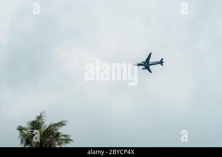 Flugzeug fliegt in einem bewölkten Himmel und Vorbereitung auf die Landung auf einer tropischen Insel. Stockfoto