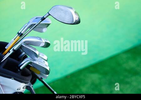 Nahaufnahme von verschiedenen Golfschlägern in Tasche auf grünem Hintergrund Stockfoto