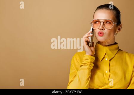 Nahaufnahme Porträt von attraktiven kaukasischen Geschäftsfrau tragen bunte gelbe Hemd isoliert auf beigem Hintergrund im Studio Stockfoto
