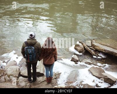 Junge Reisende, die auf Felsen am Fluss stehen und die Hände halten Stockfoto