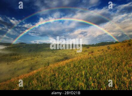 Schöne Landschaft mit Regenbogen am Himmel Stockfoto